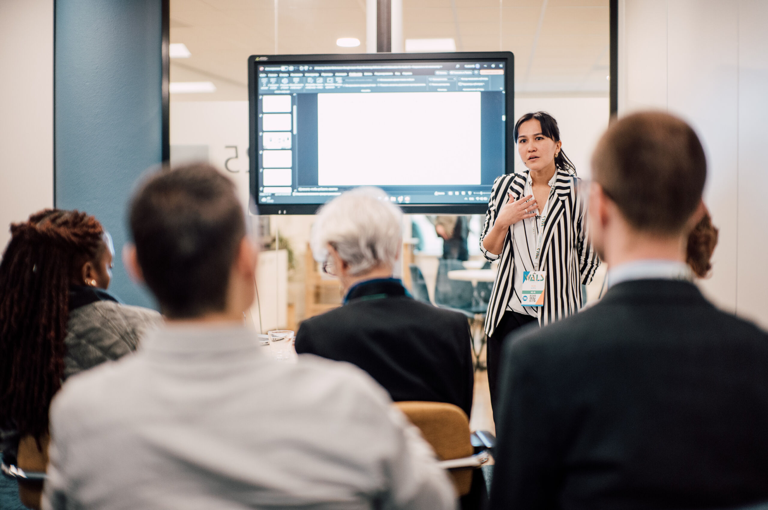 Spreker presenteert in een vergaderzaal van Nieuwe Buitensociëteit Zwolle, terwijl deelnemers aandachtig luisteren.